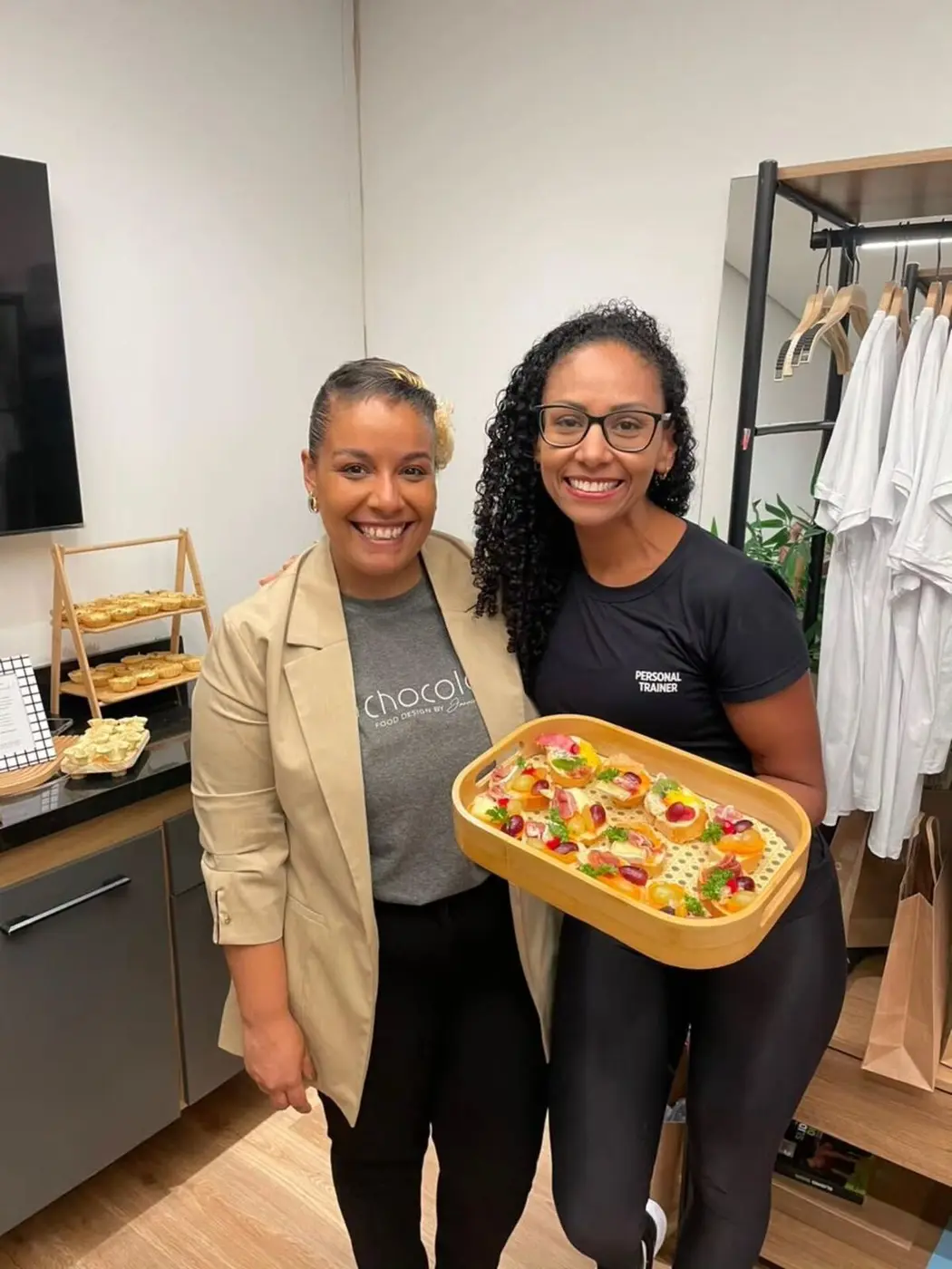 Janaina e uma colega da equipe com uma bandeja de salgados