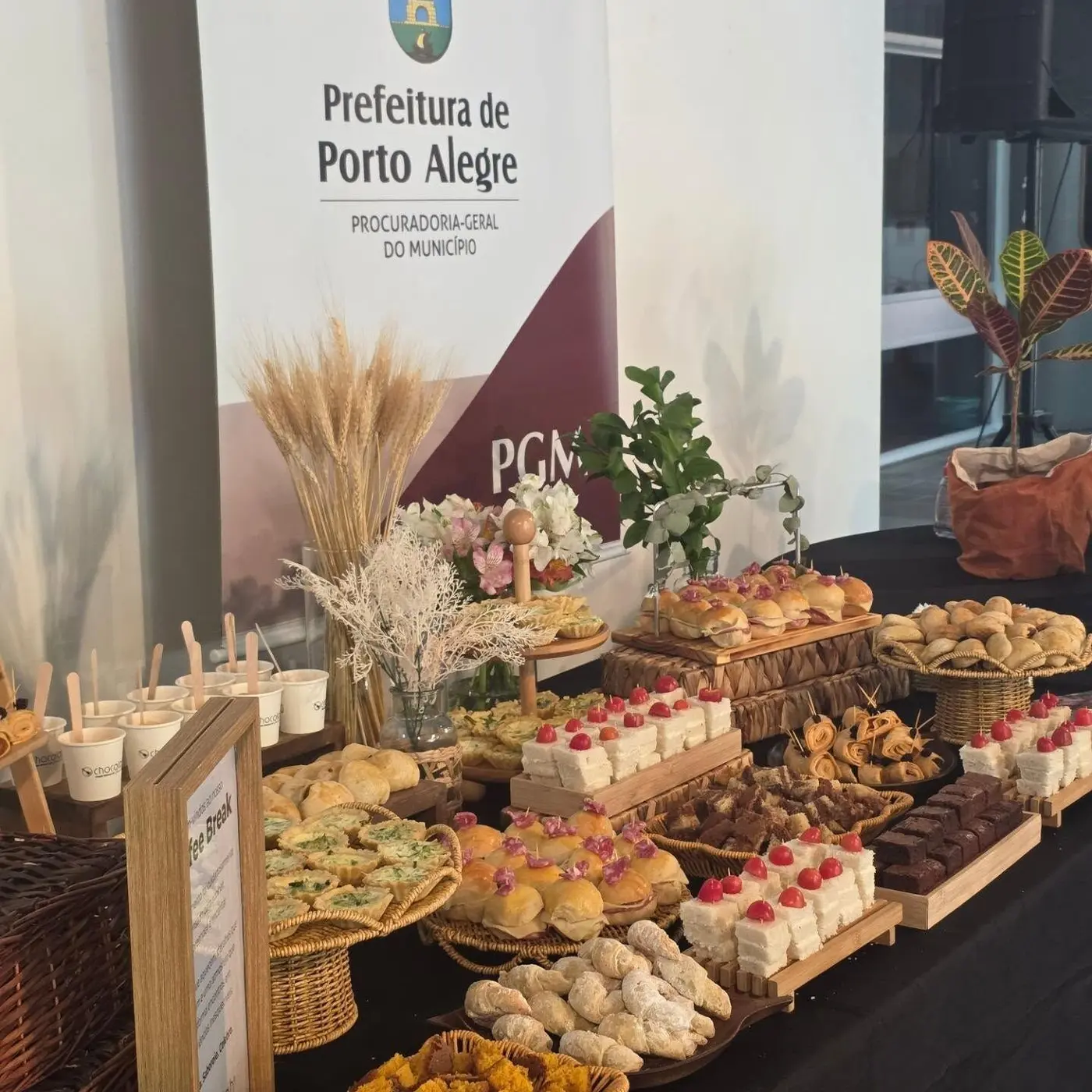 Mesa de coffee break com doces em copinhos e quiches