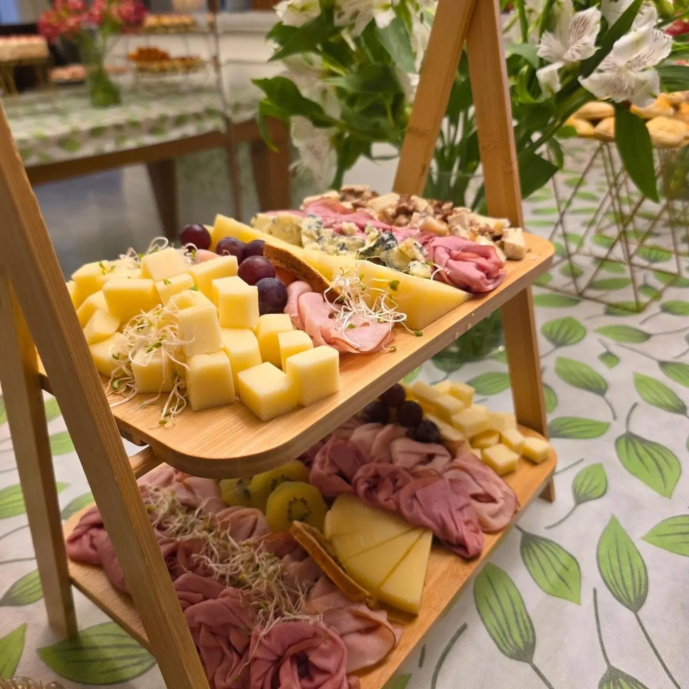 Mesa de aniversário com tábuas de frios, canapés e flores