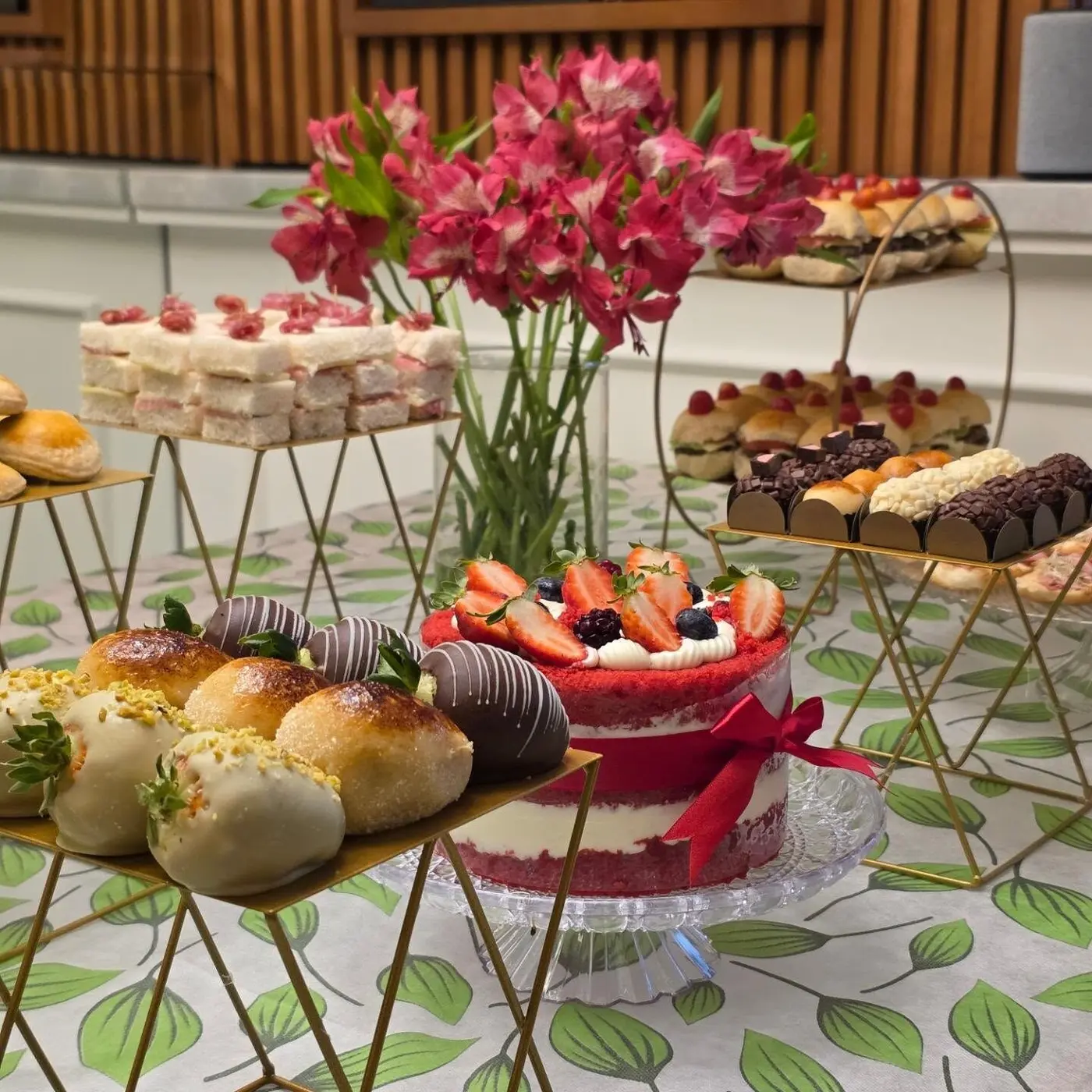 Mesa com flores rosas, doces e bolo vermelho